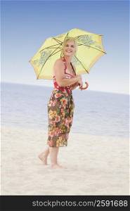 Side profile of a mature woman holding an umbrella on the beach