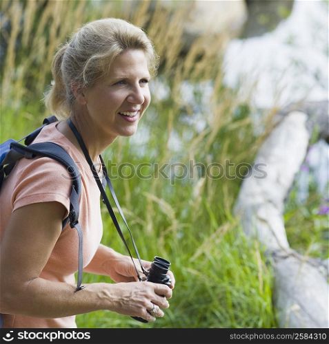 Side profile of a mature woman holding binoculars and smiling