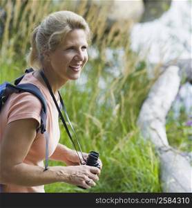 Side profile of a mature woman holding binoculars and smiling
