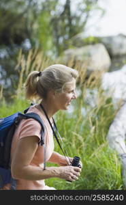 Side profile of a mature woman holding binoculars and smiling