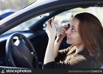 Side profile of a mature woman looking at a hand mirror