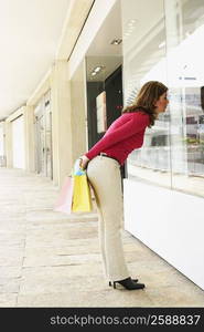 Side profile of a mature woman looking at the window display of a store