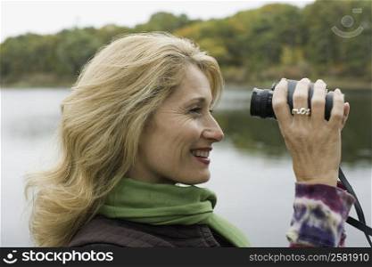Side profile of a mature woman looking through binoculars and smiling