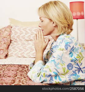 Side profile of a mature woman praying in a bedroom