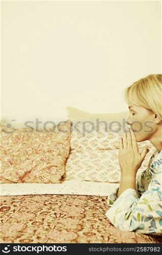 Side profile of a mature woman praying in a bedroom