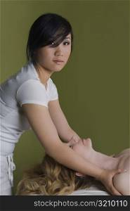 Side profile of a mature woman receiving a shoulder massage from a massage therapist