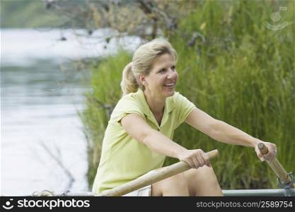 Side profile of a mature woman rowing a boat and smiling