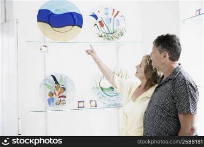 Side profile of a mature woman showing ceramic paintings to a senior man