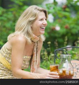 Side profile of a mature woman sitting at a table and drinking ice tea