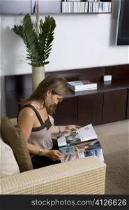 Side profile of a mature woman sitting in an armchair and reading a magazine