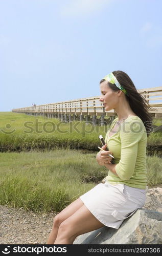 Side profile of a mature woman sitting on a stone and holding a book