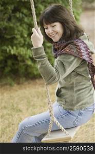 Side profile of a mature woman sitting on a swing and smiling