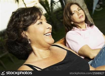Side profile of a mature woman sitting with her friend and smiling