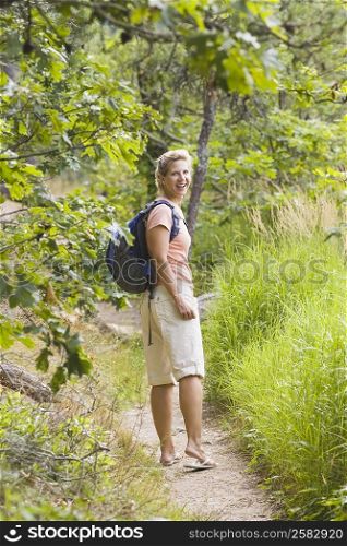 Side profile of a mature woman standing and smiling in a forest