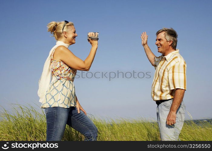 Side profile of a mature woman taking a picture of a mature man with a digital camera