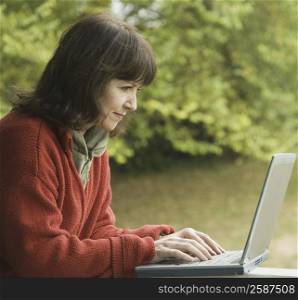Side profile of a mature woman using a laptop and smiling