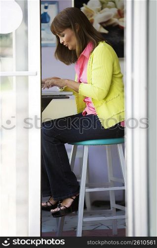 Side profile of a mature woman using a laptop in a cafe