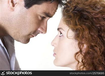 Side profile of a mid adult man and a young woman staring at each other