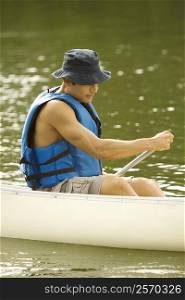Side profile of a mid adult man boating in a river