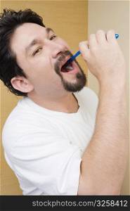 Side profile of a mid adult man brushing his teeth
