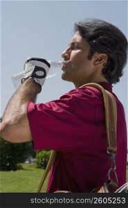 Side profile of a mid adult man drinking water from a water bottle