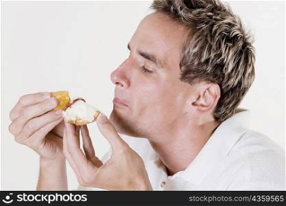 Side profile of a mid adult man eating a fruit tart