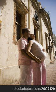 Side profile of a mid adult man embracing a pregnant young woman from behind, Santo Domingo, Dominican Republic