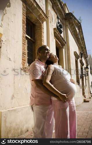 Side profile of a mid adult man embracing a pregnant young woman from behind, Santo Domingo, Dominican Republic