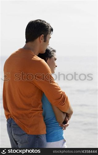 Side profile of a mid adult man embracing a young woman from behind