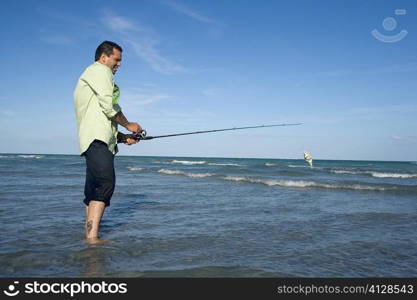 Side profile of a mid adult man fishing in the sea