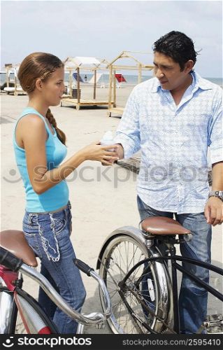 Side profile of a mid adult man giving ice-cream to a young woman