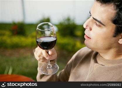 Side profile of a mid adult man holding a glass of red wine