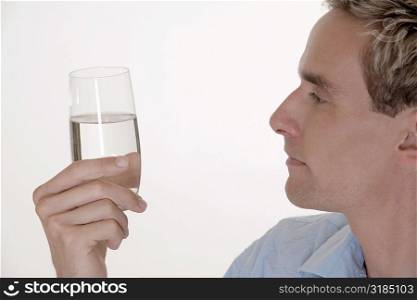 Side profile of a mid adult man holding a glass of water