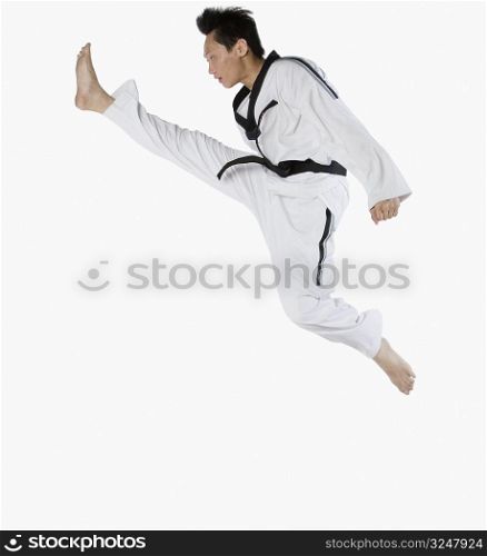 Side profile of a mid adult man jumping and practicing martial arts