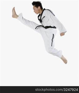 Side profile of a mid adult man jumping and practicing martial arts