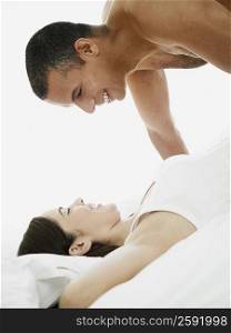 Side profile of a mid adult man leaning over a young woman lying on the bed