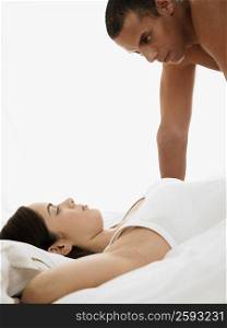 Side profile of a mid adult man looking at a young woman lying on the bed
