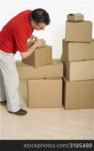 Side profile of a mid adult man packing cardboard boxes