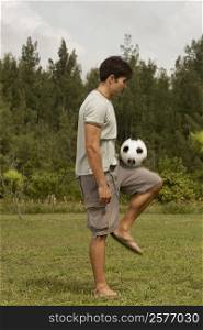 Side profile of a mid adult man playing with a soccer ball