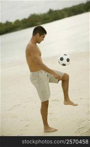 Side profile of a mid adult man playing with a soccer ball on the beach