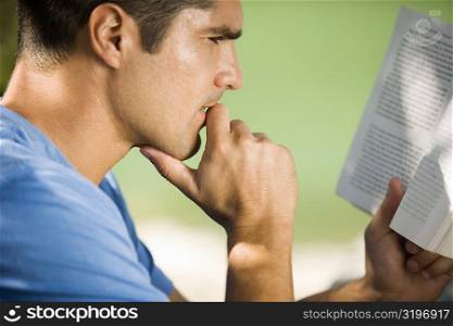 Side profile of a mid adult man reading a book