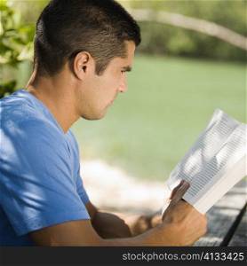 Side profile of a mid adult man reading a book