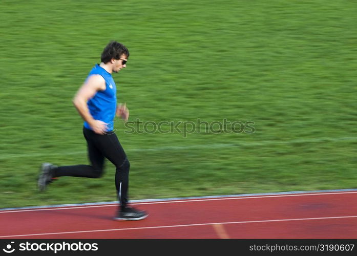 Side profile of a mid adult man running on a sports track