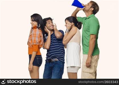 Side profile of a mid adult man shouting into a megaphone behind his friends