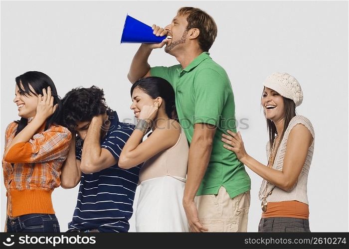 Side profile of a mid adult man shouting into a megaphone between his friends