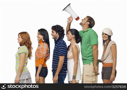 Side profile of a mid adult man shouting into a megaphone between his friends