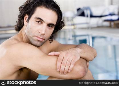 Side profile of a mid adult man sitting at the poolside