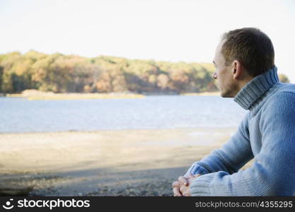 Side profile of a mid adult man sitting with his hands clasped