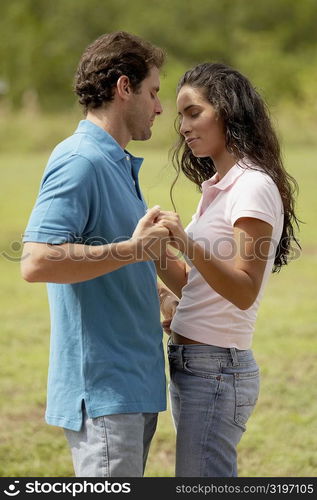 Side profile of a mid adult man standing and holding a young woman&acute;s hand