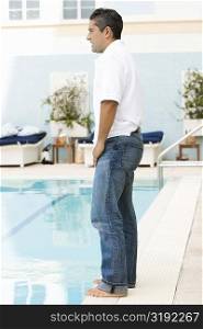 Side profile of a mid adult man standing at the poolside